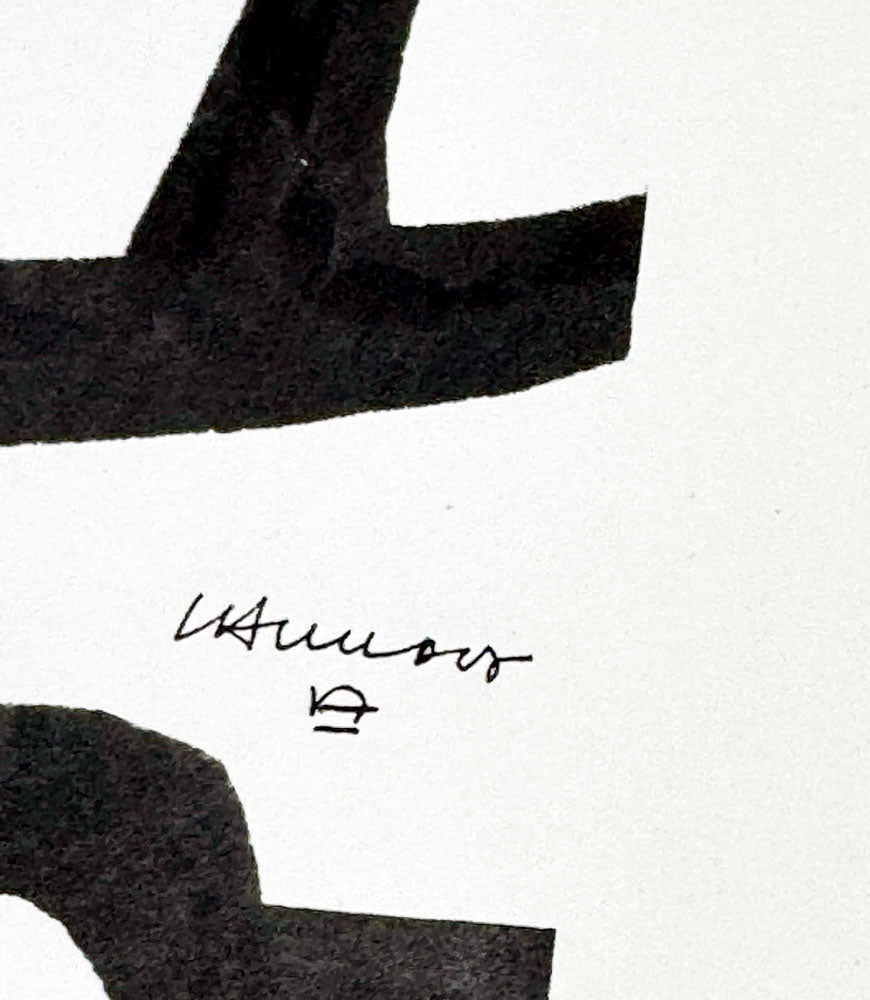 Close-up of a black ink abstract brushstroke on white paper, with a small cursive signature Chillida and small mark below it.