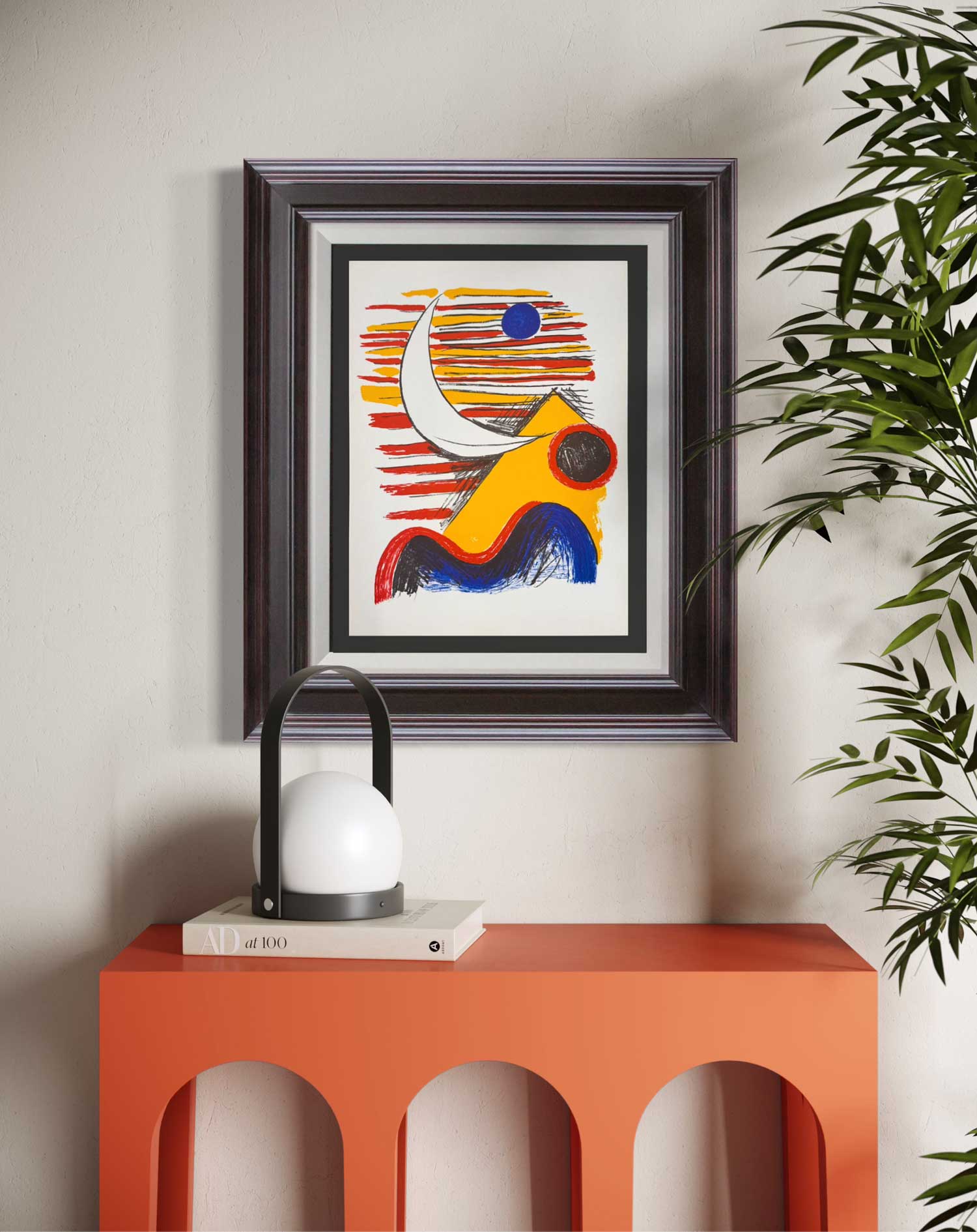 Calder lithograph framed abstract artwork on a wall above an orange console table with a lamp.