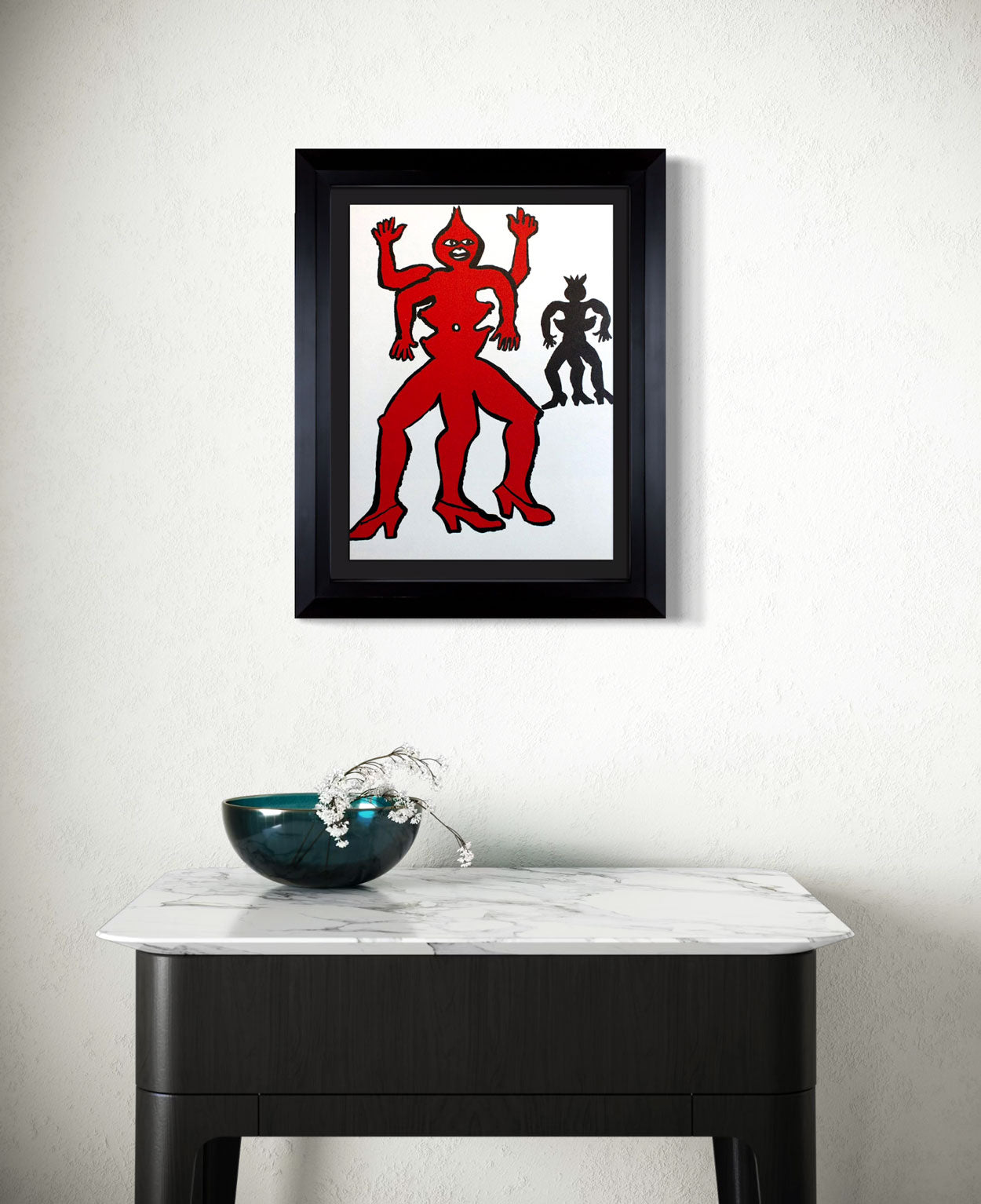 Framed Calder Lithograph of a red figure on a white background above a marble table.